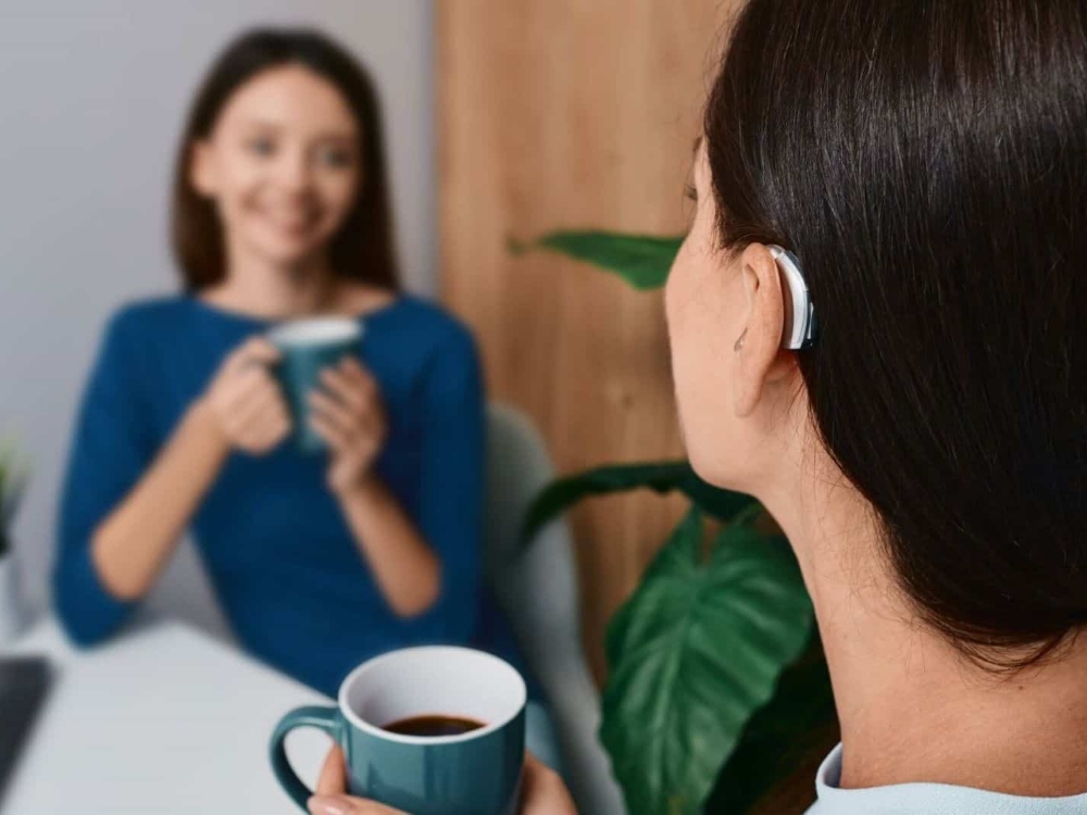 Woman wearing a receiver-in-canal hearing aid during a conversation — hearing aid styles fitted at Physicians Hearing Clinic in Sarasota, FL
