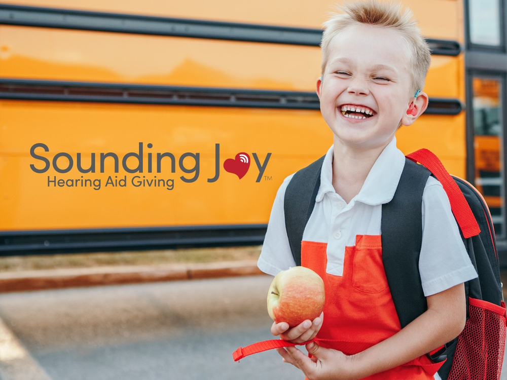 Audiologist fitting a child with hearing aids through the Sounding Joy charity partnership at Physicians Hearing Clinic in Sarasota, FL